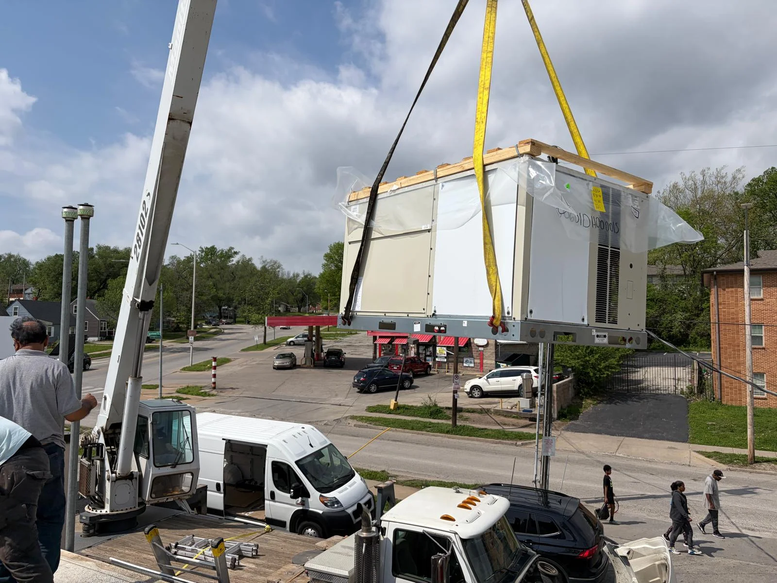 Crane lifting new packaged rooftop HVAC unit to commercial building roof